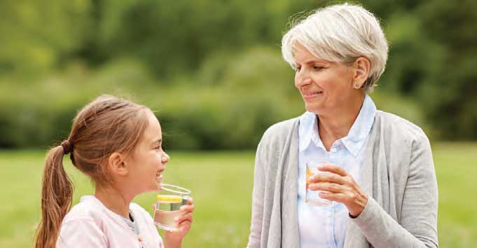 Retired woman and granddaughter drinking water