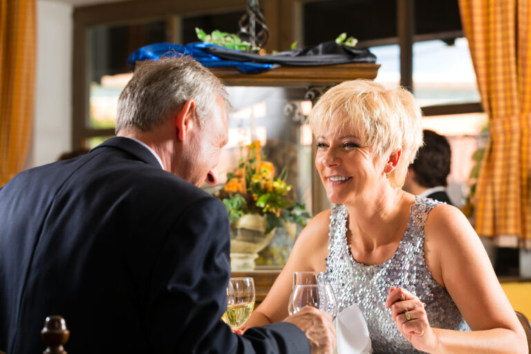 Senior couple experiencing quality senior living dining with gourmet food at elegant table setting
