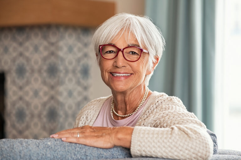 A senior woman sits on the couch in her apartment