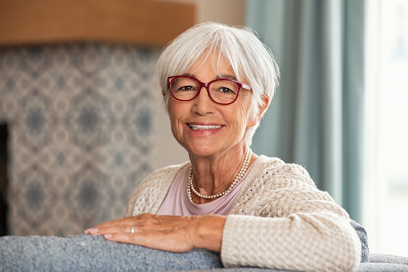 A senior woman sits on the couch in her apartment