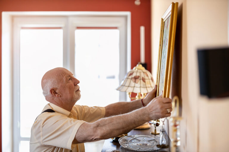 An older adult man decorating a senior living apartment