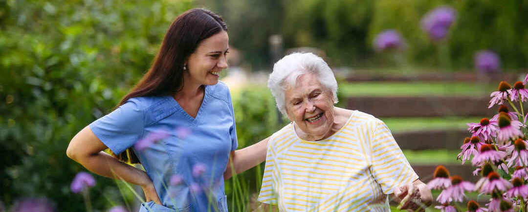 Woman and caretaker outside in a garden looking at flowers