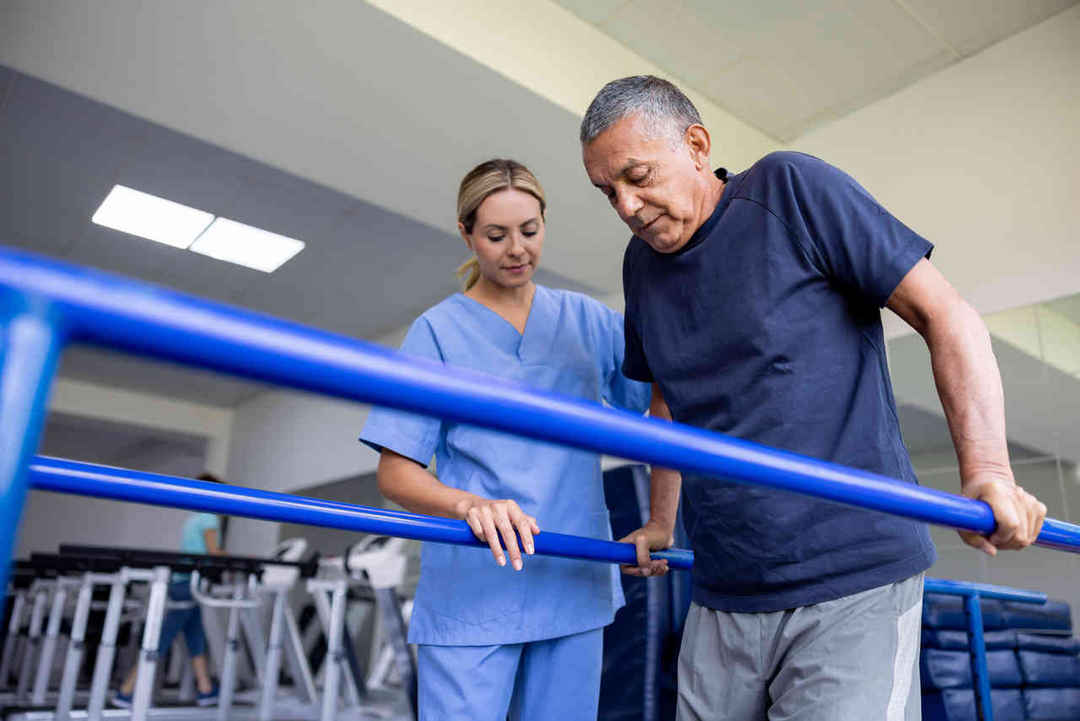 Trainer assisting man in training in gym room