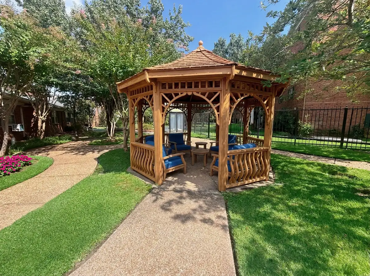 Small gazebo outside in the summertime sitting on the green grass with a sidewalk up to it