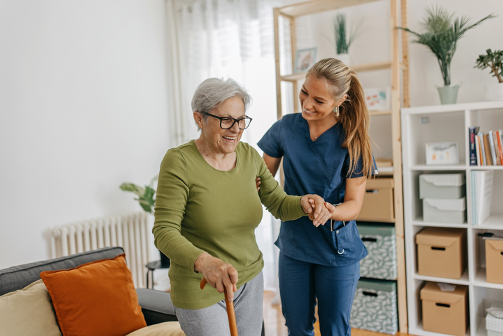caretaker helping woman from a seat in the living room