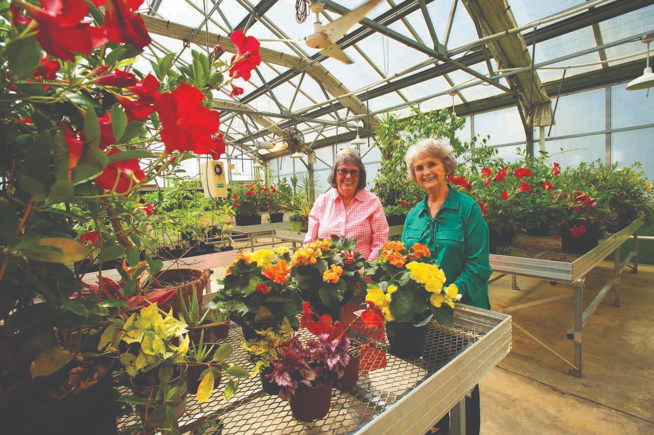 2 women in the greenhouse with colorful flowers