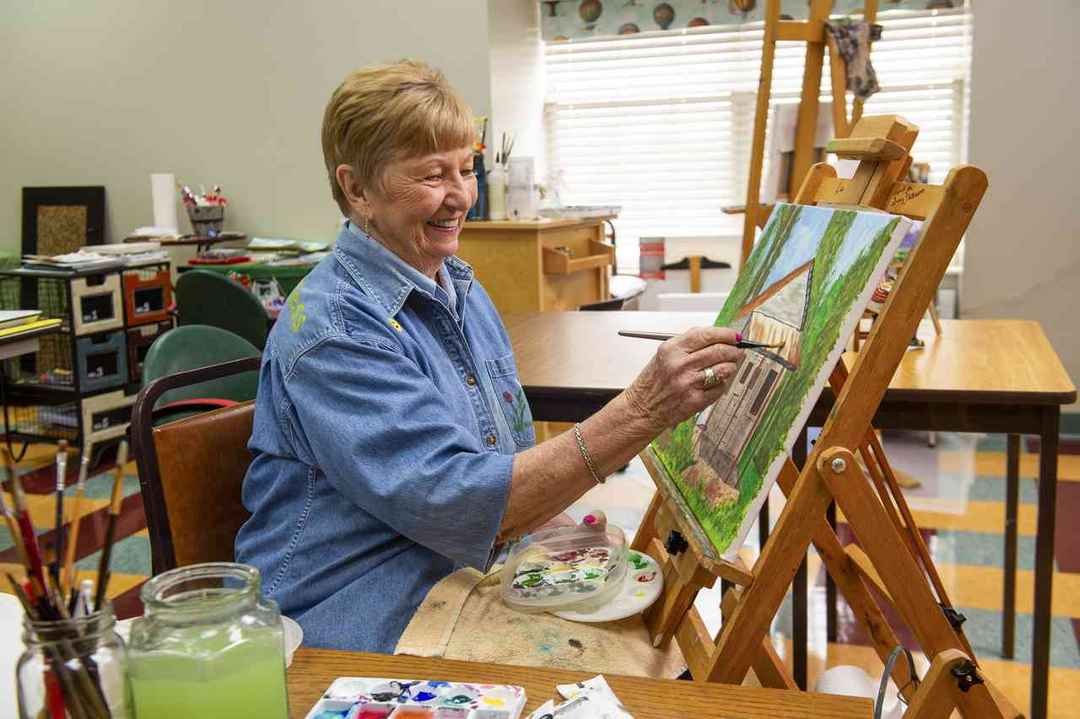 Woman standing and painting on a canvas in an art room