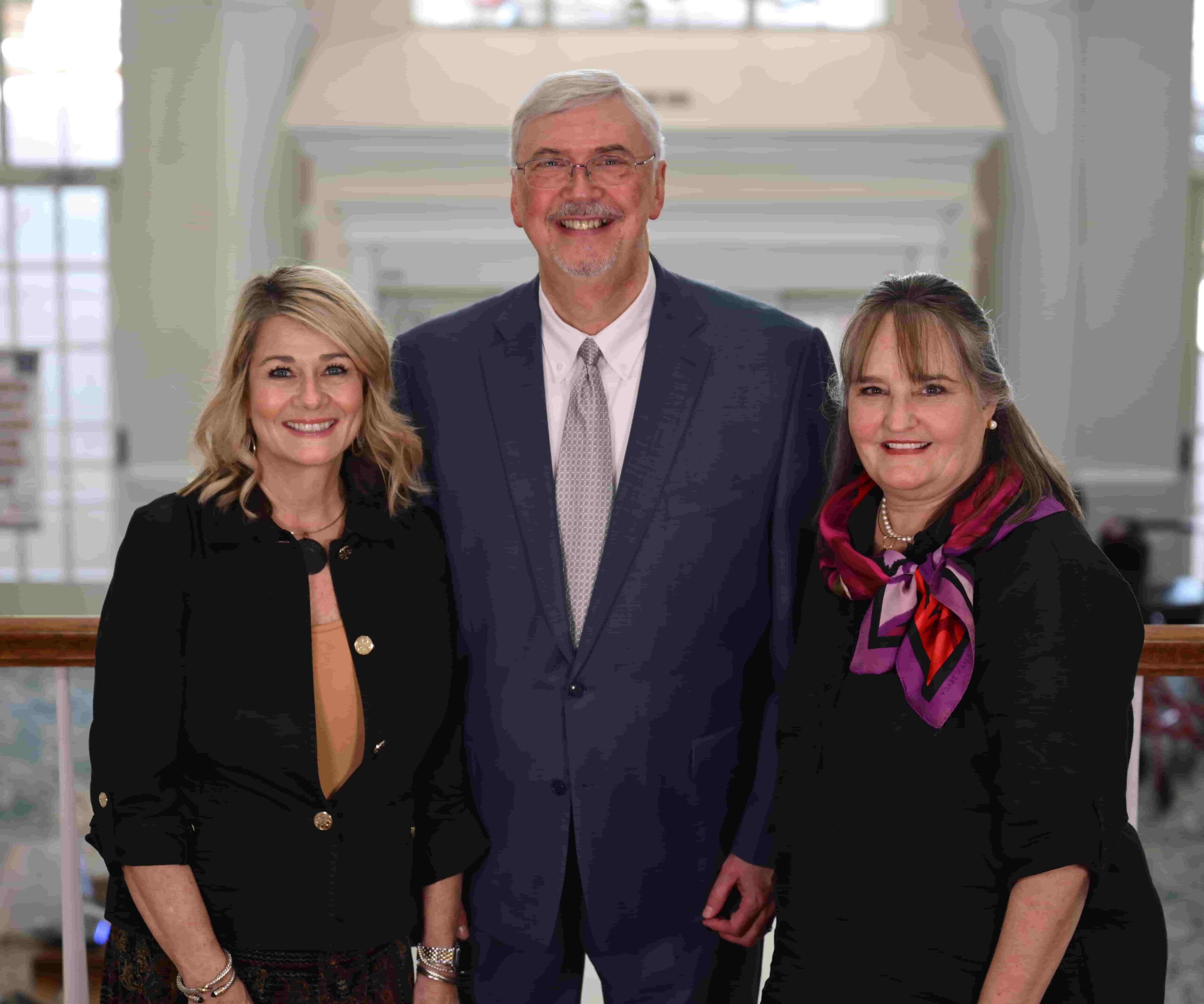 Marketing team of 3 people standing in front of a grand fireplace