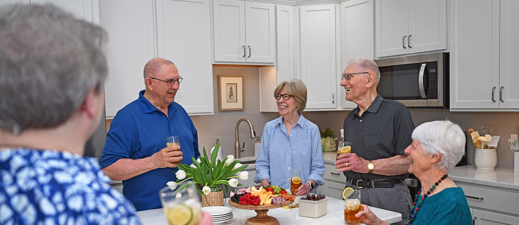 seniors drinking wine around kitchen