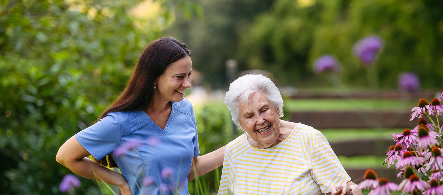 Home nurse spending time with elderly lady patient in garden.